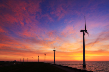 Obraz premium Beautiful sunset at the dike with wind turbines at the Markermeer in the Netherlands 