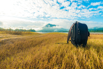 Black backpack on the yellow grass background with mountain view