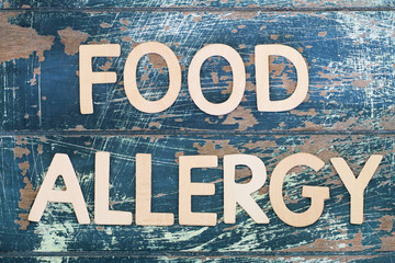 Food allergy written on rustic wooden surface
