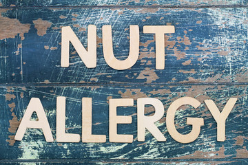 Nut allergy written on rustic wooden surface
