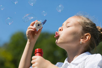 Charming girl blowing soap bubbles