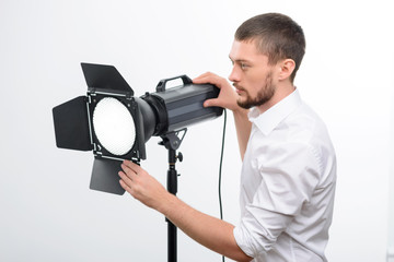 Young male professional photographer is busy fixing the spotlight
