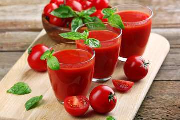 Glasses of tomato juice on wooden table, closeup