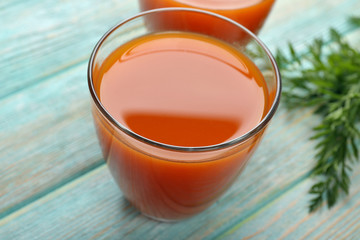 Glasses of carrot juice on wooden background