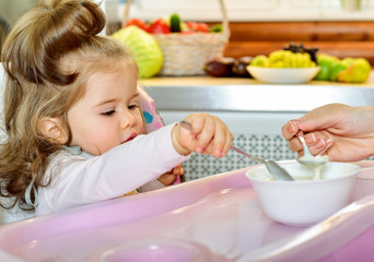 Mother spoon-feeds the child.  Feeding baby. Baby food.