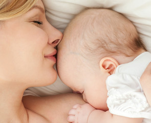 Young mother and her baby, sleeping in bed. Mother and baby. 