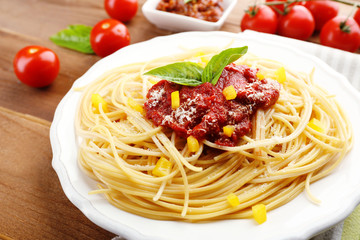 Spaghetti with tomato sauce, paprika and cheese on white plate, on color wooden background