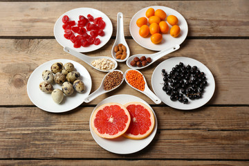 Different products on saucers and spoons on wooden table close up