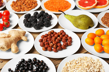 Different products on saucers on wooden table close up