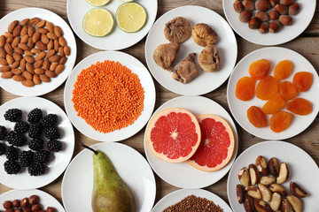 Different products on saucers on wooden table, top view