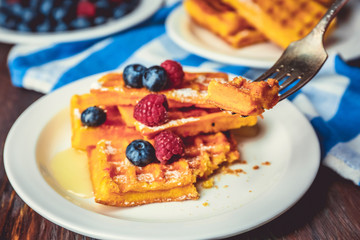 Sweet homemade waffles with forest berries and sauce on table background