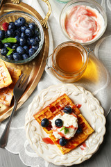 Sweet homemade waffles on plate, on color wooden background