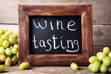 old square chalk scripted frame with grape on wooden background