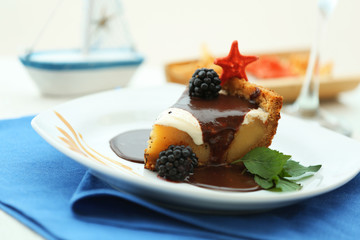 Delicious cake under chocolate glaze with blackberry on blue serviette