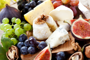 Cheese platter: variety of cheeses on wooden plate with fruits