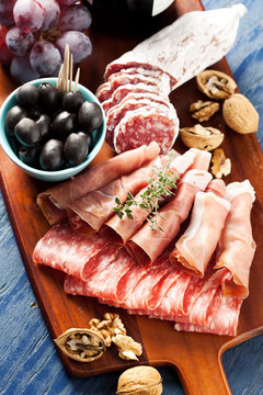 Charcuterie assortment and black olives on wooden background