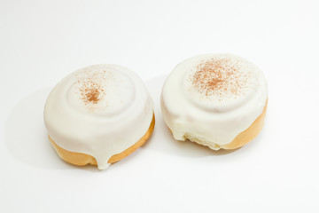 two buns with icing and cinnamon isolated on white