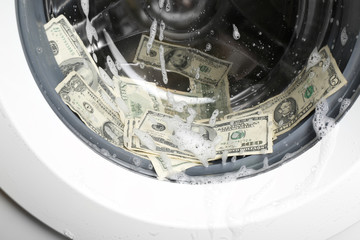 Laundering of dirty money in washing machine, close up