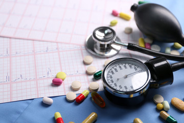 Blood pressure meter, pills and stethoscope, on blue uniform background