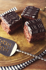Sweet chocolate cakes and spatula on tray with stripped cotton serviette, close up