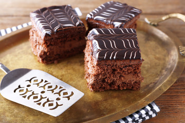 Sweet chocolate cakes and spatula on tray with stripped cotton serviette, close up