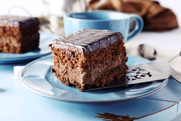 Served table with a cup of tea and chocolate cakes on blue plates close-up