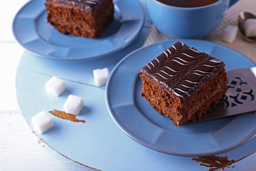 Served table with a cup of tea and chocolate cakes on blue plates close-up