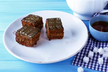 Served table with a cup of tea and chocolate cakes on white plates close-up