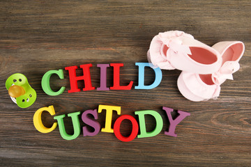 Baby's booties, dummy and colourful letters regarding child-custody and family-law concept