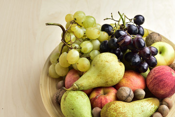 Autumn fruits on a wooden plate