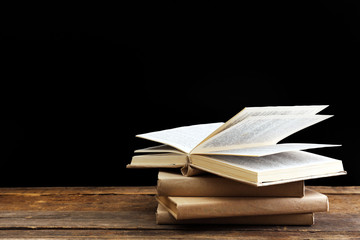 Old books on wooden table against black background