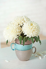 Beautiful flowers in vase on table in room on bright background