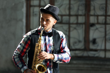 Man with saxophone outside near the brick wall
