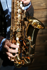 Obraz premium The musician with sax on wooden background, close up