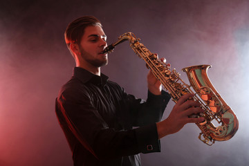 Plakat Young man professionally plays sax in red smoke
