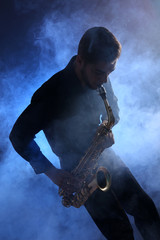 Obraz na płótnie Canvas Elegant saxophonist plays jazz in blue smoke