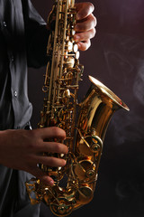 Fototapeta premium Musician in black shirt with sax on dark background, close up