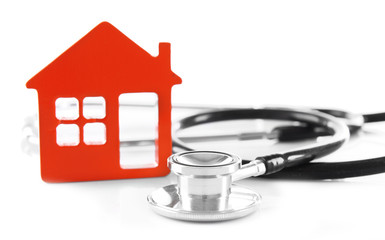 Concept of family medicine - red plastic house and stethoscope isolated on white background