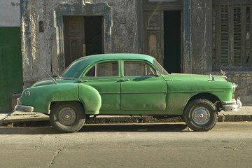 An old green car sitting in front of old building in Old Havana, Cuba