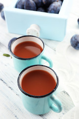 Plum Juice in mugs with fresh fruits
