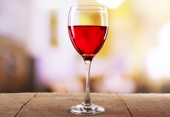 Red wine glass on wooden table against unfocused background