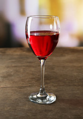 Red wine glass on wooden table against unfocused background