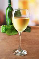 White wine glass  with bottle and grape on wooden table against unfocused background