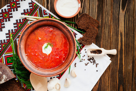 
Ukrainian national cuisine , red borscht with sour cream , herbs , garlic and rye bread on a wooden background