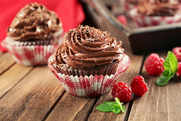 Chocolate cupcakes and raspberries on wooden background