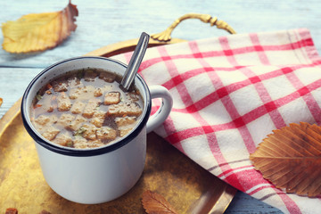 Mug of soup on metal tray on a table