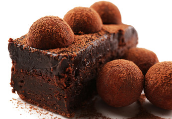 Slice of chocolate cake with a truffle on plate closeup