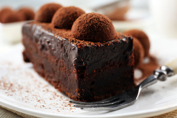 Slice of chocolate cake with a truffle on plate closeup
