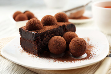 Slice of chocolate cake with a truffle on plate closeup