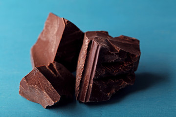 Dark chocolate pieces on color wooden background
